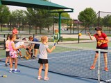 An instructors teaching children how to play tennis