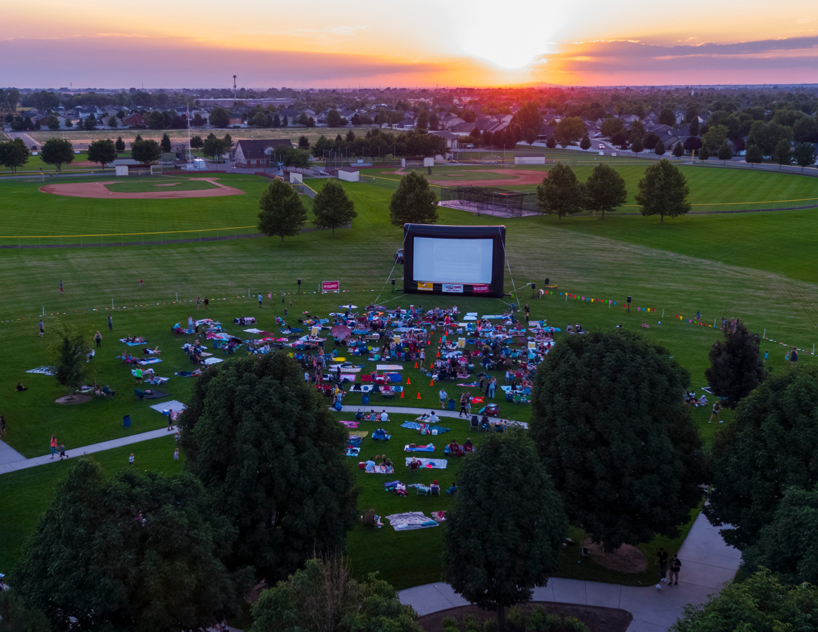 Aerial view of Settlers Park in the sunset with a crowd gathered for a movie night